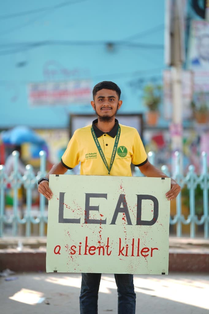 Tanvir Ahmad holding a LEAD a silent killer poster during International Lead Poisoning Prevention Week 2025